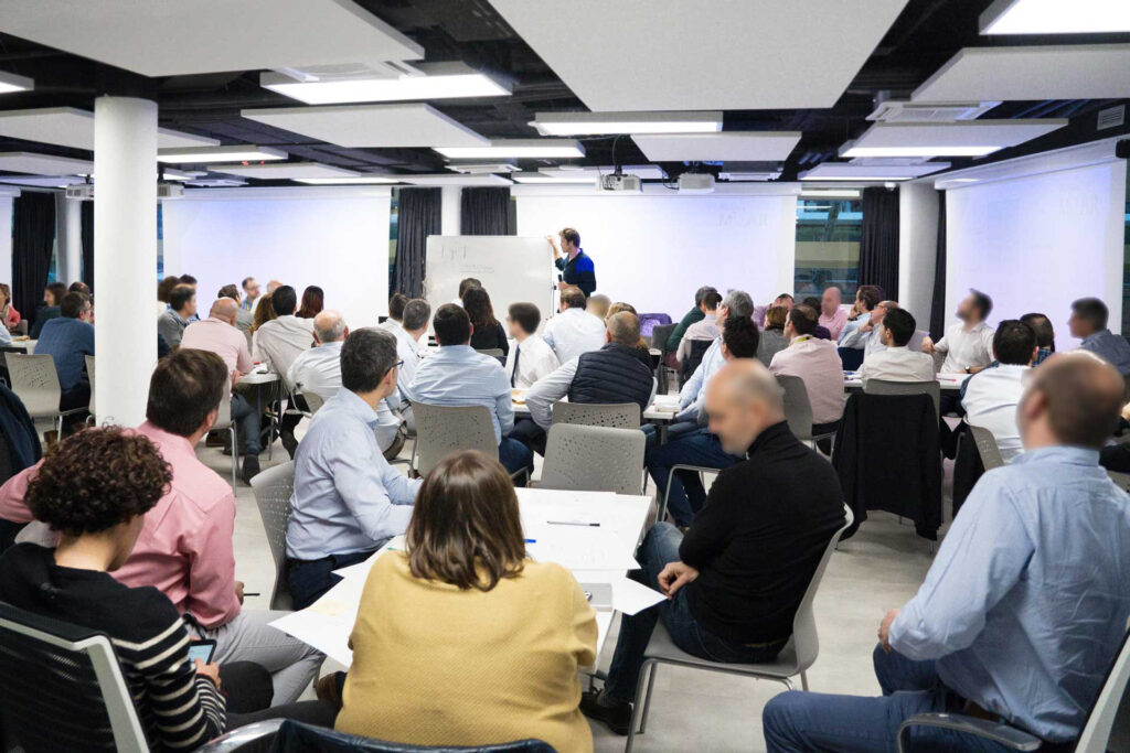 Fotografía de Ferran Tort impartiendo una sesión formativa en un aula moderna, frente a un público numeroso sentado en mesas de trabajo y atento a la presentación.