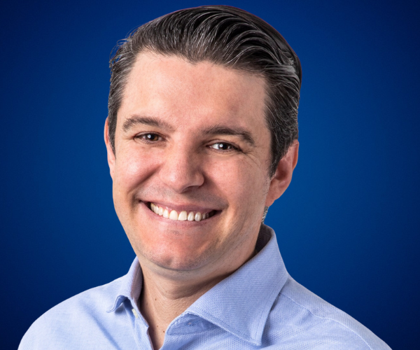 Guillermo González sonriendo frente a un fondo azul.