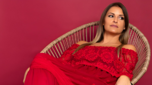 Rebeca Barzuna, experta en marca personal, vestida de rojo y sentada en una silla con fondo del mismo tono, reflejando confianza y autenticidad.