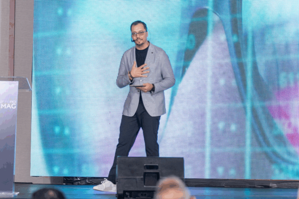 Andrés Conde en el escenario durante una conferencia, con gesto expresivo y fondo digital, hablando sobre inteligencia artificial y propósito humano.