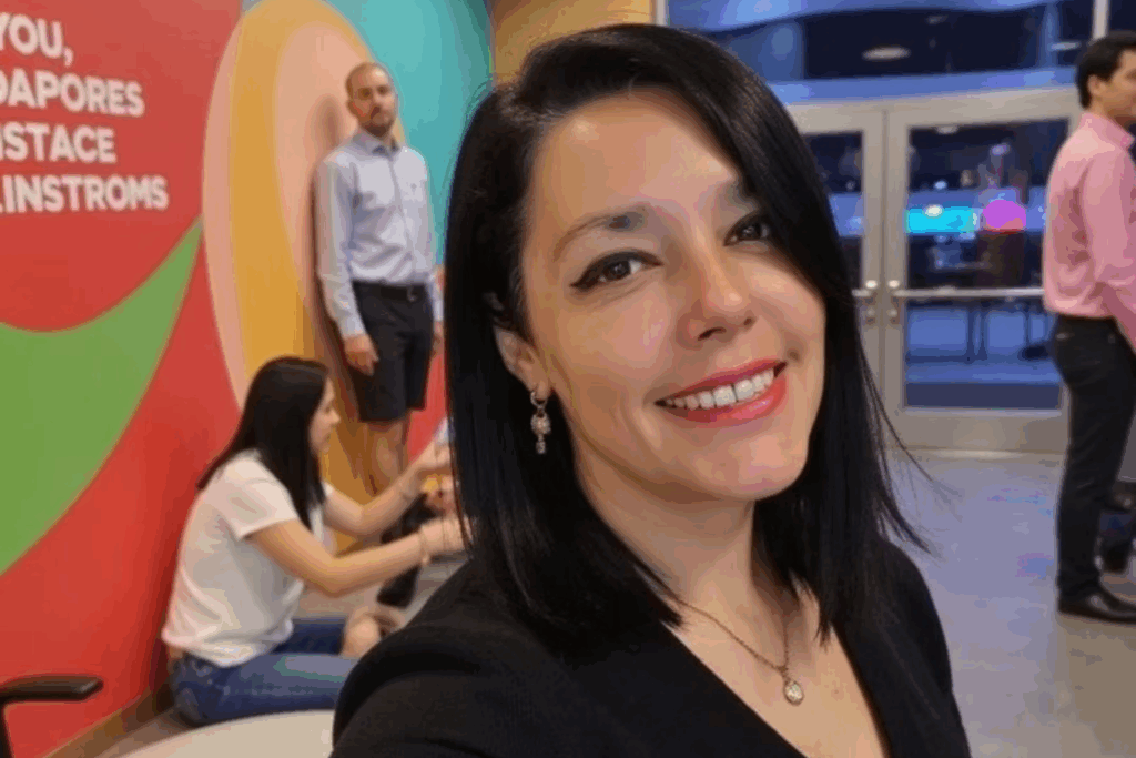 Patricia González sonriendo en un evento, rodeada de personas en un entorno corporativo colorido.