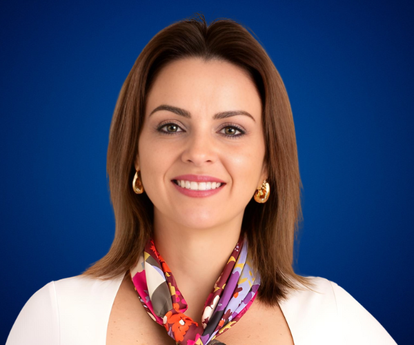 Cristina Jaramillo sonriendo, conferencista experta en liderazgo femenino, marca personal e inteligencia emocional, sobre fondo azul.
