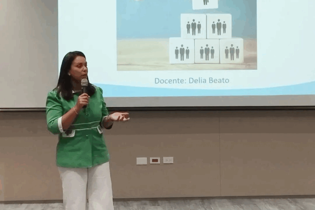 Delia Beato impartiendo conferencia sobre liderazgo y desarrollo organizacional frente a su audiencia.